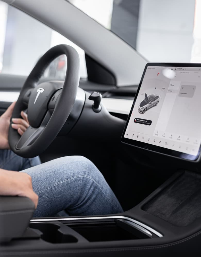 Person sitting in the driver's seat of a Tesla while viewing dashboard screen | Hands-free location sharing